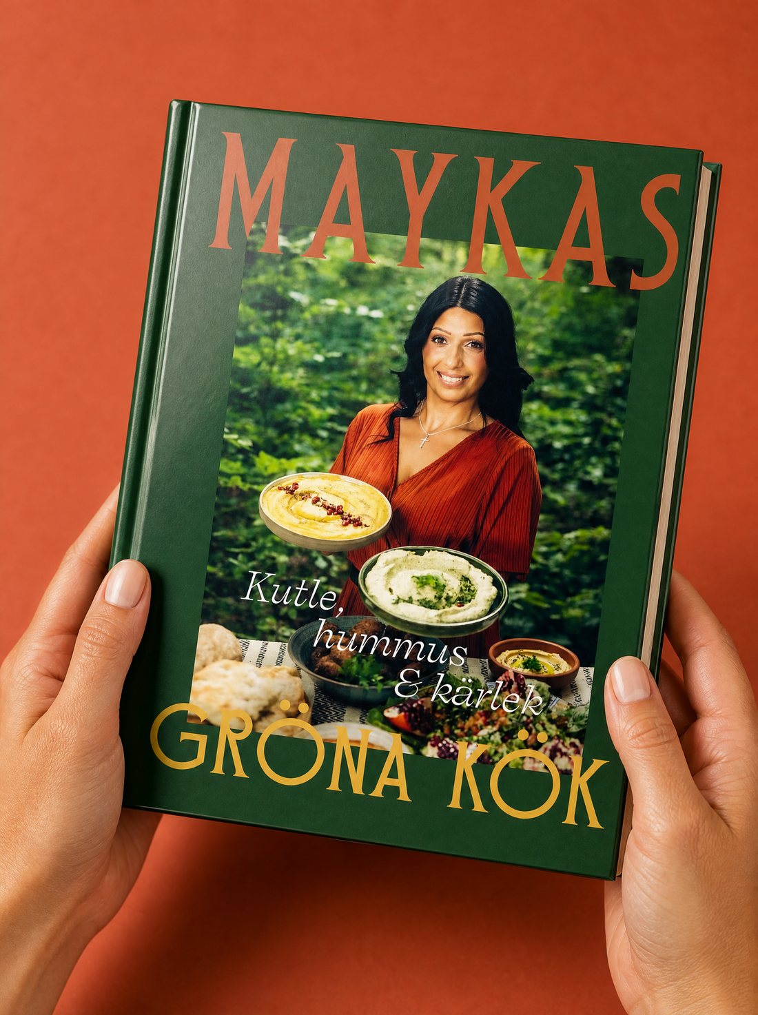 Två händer håller boken Maykas gröna kök